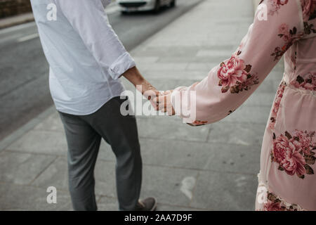 Nahaufnahme der junge Paar Hand in Hand. Liebe und Partnerschaft Ziele. Der Mann und die Frau zu Fuß auf die Straße. Stockfoto