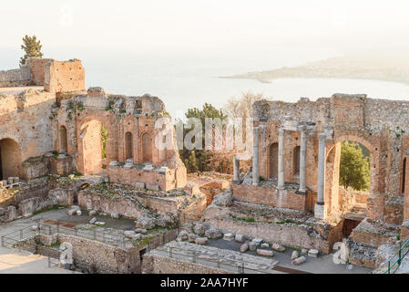 Blick auf einige Spalten und ein Bogen in die Szene des griechischen Theaters in Taormina und eine Perspektive von Giardini Naxos im Hintergrund Stockfoto