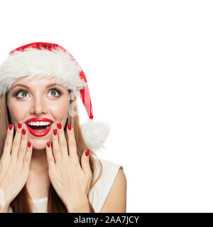 Glückliche Frau in Santa Hut mit roten Maniküre Nägel in der Nähe von roten Lippen isoliert. Überrascht Weihnachten Mädchen suchen Stockfoto