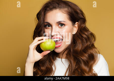 Closeup Porträt der schönen Frau mit weißen Zähnen und Apfel Obst auf gelben Hintergrund Stockfoto