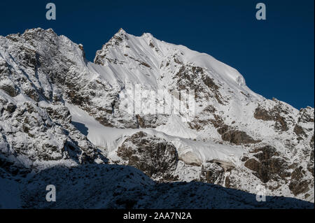 Sonnenlicht leuchtet die oberste Spitze der Naya Kanga, die überschattet die Gangja La, ein Pass aus dem Langtang Tal, Nepal. Stockfoto