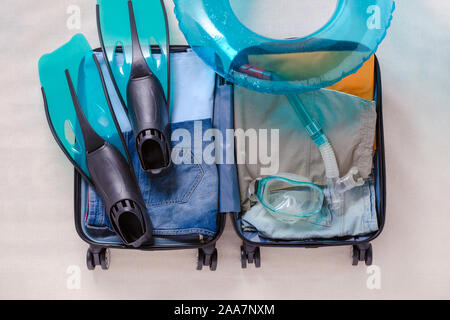 Open travel Koffer mit Kleidung und Flossen und Schnorchel Maske, Ansicht von oben Stockfoto