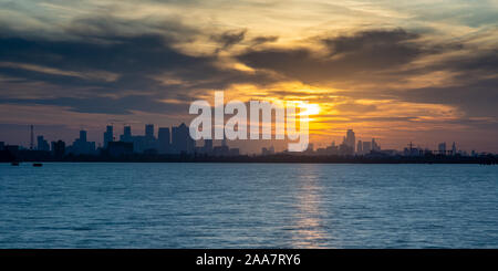 Die skylines von der Londoner City und den Docklands Canary Wharf Geschäftsviertel sind gegen die untergehende Sonne Silhouette wie vom Fluss Tham gesehen Stockfoto