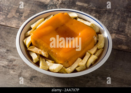 Typisch portugiesische francesinha Sandwich mit Pommes frites auf hölzernen Tisch Stockfoto