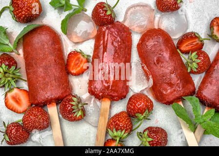 Hausgemachte Eis am Stiel mit Erdbeeren, Eis am Stiel auf Sticks, Ansicht von oben, flach Stockfoto