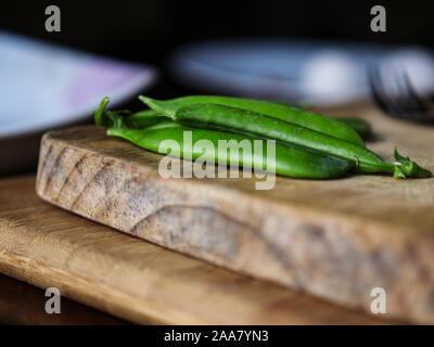 Grüne Erbsen auf einem hölzernen Schneidebrett Stockfoto