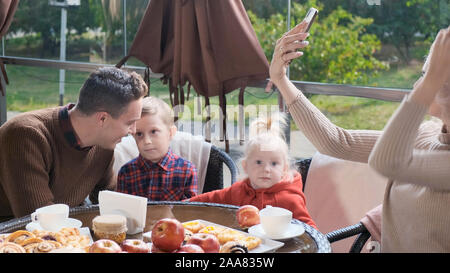 Familie in einem Café auf der Terrasse. Mom macht selfie Stockfoto