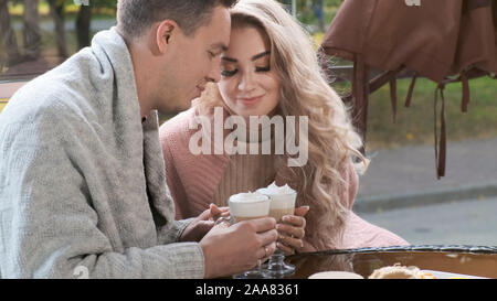 Paar in einem Café auf der Terrasse. Die Hände der liebenden Mann und Frau halten Sie Tassen mit Cappuccino und Latte Stockfoto