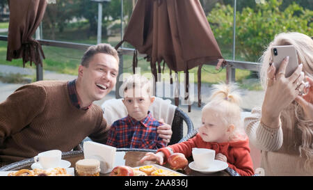 Familie in einem Café auf der Terrasse. Mom macht selfie mit Familie Stockfoto