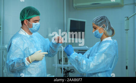 Der Arzt ist Vorbereitung für die Chirurgie. Krankenschwester hilft dem Arzt ein Handschuhe im Operationssaal zu tragen Stockfoto