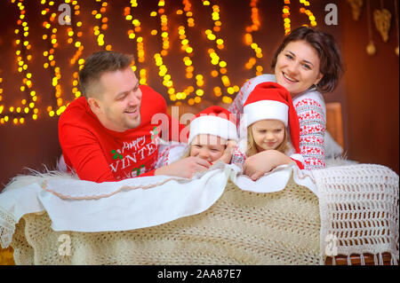 Porträt einer glücklichen Familie. Sitzung im Schlafanzug auf dem Bett und Spaß haben. Weihnachten Morgen. Stockfoto