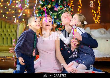 Glückliche Familie feiert in einem Zimmer in der Nähe der festlichen Weihnachtsbaum. Warten auf den Urlaub Stockfoto