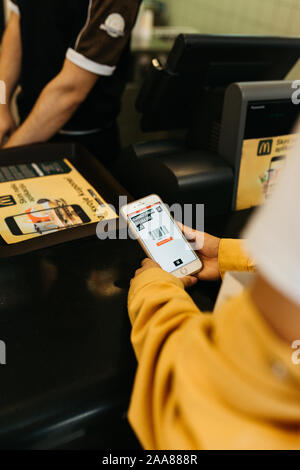 Junge schöne Frau essen Bestellen innerhalb von McDonald's in Sarajewo. Sie hält ihr Telefon. Nahaufnahme Foto. Stockfoto