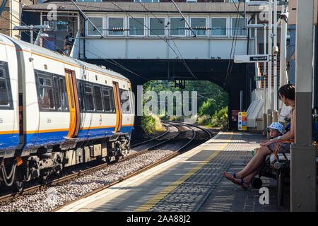 London, England, Großbritannien - 24 Juli, 2019: Passagiere warten auf einen Zug am Bahnhof Kensal Rise an einem sonnigen Sommertag auf der London Overground. Stockfoto