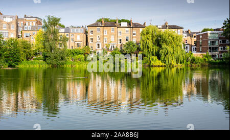 London, England, Großbritannien - 4. Juli 2019: Stadthäuser und Bäume sind in Hampstead Nr. 2 Teich auf der London Hampstead Heath Park wider. Stockfoto