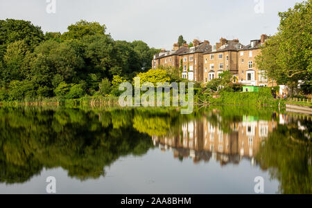 London, England, Großbritannien - 4. Juli 2019: Stadthäuser und Bäume sind in Hampstead Nr. 2 Teich auf der London Hampstead Heath Park wider. Stockfoto