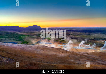 Island. Dampf steigt über die heißen Quellen bei Sonnenuntergang. Thermalquellen. Erneuerbare Energien. Stockfoto