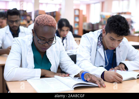 Eine Gruppe von jungen Medizinstudenten mit mixed-race Chirurgen untersucht diese Vorgänge in einem Laptop. Stockfoto