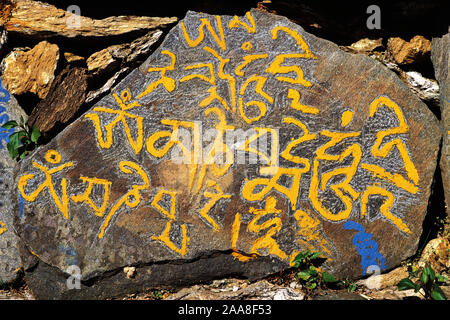 Mähne-steinerne mit der buddhistischen Friedensbotschaft "Om Mane Padme Hom" an der Seite einer Strecke in Ost-Nepal Stockfoto