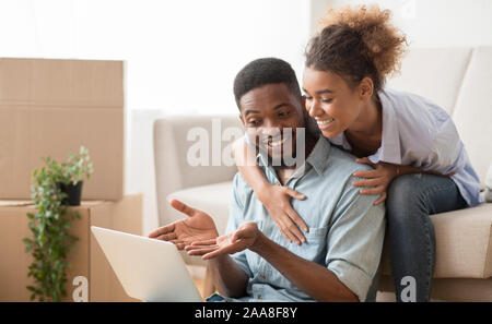 Mann mit Laptop zeigt etwas Frau sitzt auf der Couch Indoor Stockfoto