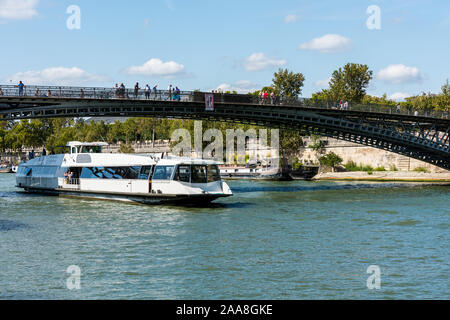 Kreuzfahrtschiff durch die Eiserne Brücke acrossing der Seine an einem sonnigen Tag in Paris, Frankreich. Stockfoto