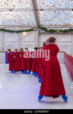 Winchester, Hampshire, UK. 20. November 2019. Chorknaben Schlittschuhlaufen auf der Eisbahn in ihrer berühmten roten Roben an der Winchester Cathedral als Weihnachtsfeier erhalten unterwegs mit der festliche Tradition der Vorsänger Skaten rund um die Eisbahn vor seiner Eröffnung morgen. Die Eisbahn ist Teil der Kathedrale von Winchester Weihnachtsmarkt, einer der grössten im Land. Credit: Carolyn Jenkins/Alamy leben Nachrichten Stockfoto