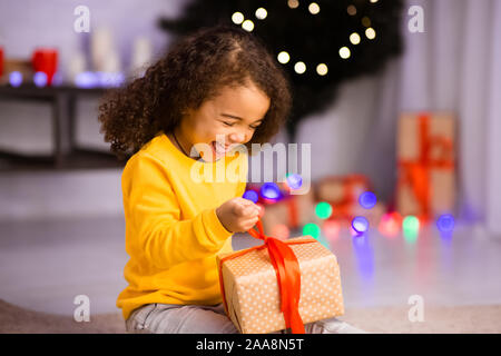 Emotionale afro girl Öffnen gewünschten Weihnachtsgeschenk Stockfoto