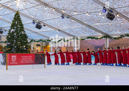 Winchester, Hampshire, UK. 20. November 2019. Chorknaben Schlittschuhlaufen auf der Eisbahn in ihrer berühmten roten Roben an der Winchester Cathedral als Weihnachtsfeier erhalten unterwegs mit der festliche Tradition der Vorsänger Skaten rund um die Eisbahn vor seiner Eröffnung morgen. Die Eisbahn ist Teil der Kathedrale von Winchester Weihnachtsmarkt, einer der grössten im Land. Credit: Carolyn Jenkins/Alamy leben Nachrichten Stockfoto