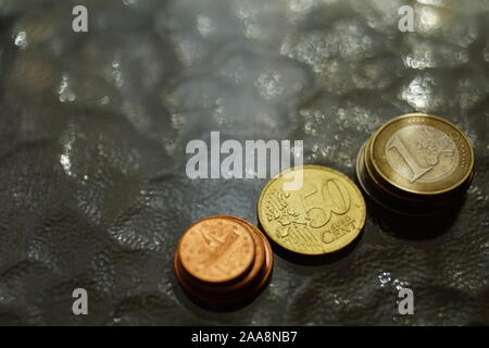 Stapel von glänzenden Münzen auf einem Glastisch Stockfoto