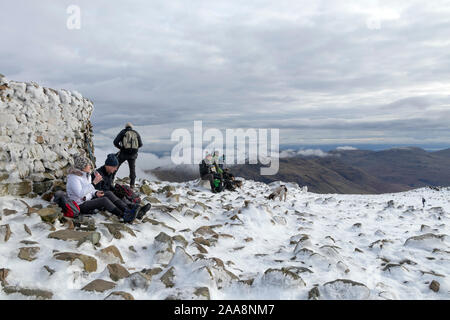 Wanderer genießen eine Pause auf dem Gipfel des Scafell Pike im Winter, See, Bezirk, Cumbria, Großbritannien Stockfoto