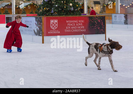 Winchester, Hampshire, UK. 20. November 2019. Chorknaben Schlittschuhlaufen auf der Eisbahn in ihrer berühmten roten Roben an der Winchester Cathedral als Weihnachtsfeier erhalten unterwegs mit der festliche Tradition der Vorsänger Skaten rund um die Eisbahn vor seiner Eröffnung morgen. Die Eisbahn ist Teil der Kathedrale von Winchester Weihnachtsmarkt, einer der grössten im Land. Credit: Carolyn Jenkins/Alamy leben Nachrichten Stockfoto