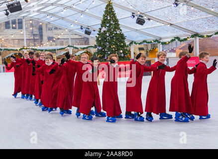 Winchester, Hampshire, UK. 20. November 2019. Chorknaben Schlittschuhlaufen auf der Eisbahn in ihrer berühmten roten Roben an der Winchester Cathedral als Weihnachtsfeier erhalten unterwegs mit der festliche Tradition der Vorsänger Skaten rund um die Eisbahn vor seiner Eröffnung morgen. Die Eisbahn ist Teil der Kathedrale von Winchester Weihnachtsmarkt, einer der grössten im Land. Credit: Carolyn Jenkins/Alamy leben Nachrichten Stockfoto