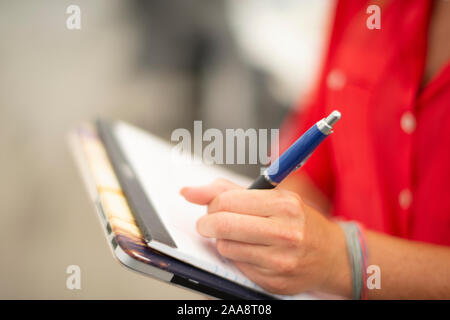 Linkshändige Frau Notizen mit einem Stift und Block Papier Stockfoto