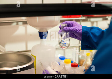 Wissenschaftler vorbereiten klare Flüssigkeit von einem Florenz Kolben in ein Labor zu hinzufügen Stockfoto