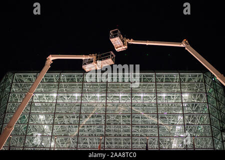 Zwei Kräne schweben über Glas Struktur in der Nacht Stockfoto