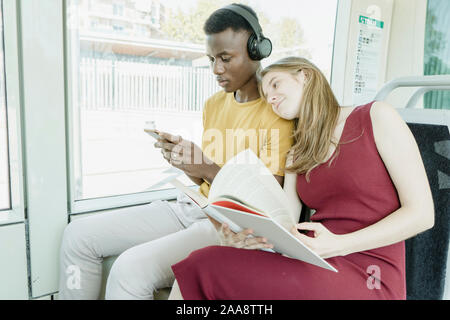 Junge Mädchen Lesen und Hören von Musik auf dem Bus Stockfoto