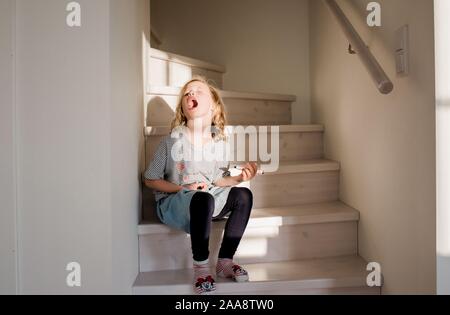 Junge Mädchen ziehen dumme Gesichter während Zeichnung auf ihre Hand und Gesicht. Stockfoto