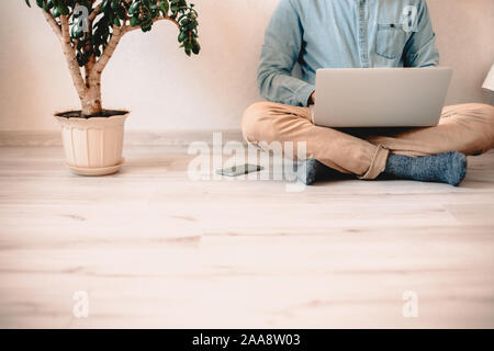 Mann mit Laptop Computer, während auf dem Boden zu Hause sitzen Stockfoto