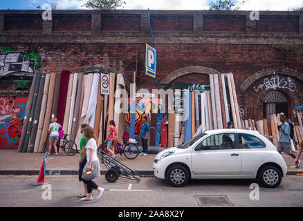 Fußgänger vorbei Teppiche für Verkauf an Sclater Straße Fleat Markt im East End von London. Stockfoto