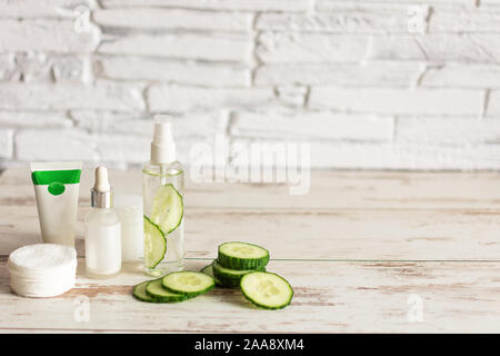 Flaschen mit hausgemachten Gurke Naturkosmetik mit grünen Gurkenscheiben und Baumwolle - Pads auf Holz- Hintergrund. Kopieren Sie Platz. Stockfoto