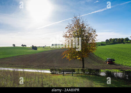 Traktor und Egge an Feld in der niederländischen Provinz Südlimburg Stockfoto