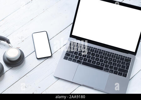 Der Laptop und Telefon mit leeren Bildschirme auf weissem Holztisch. Arbeitsbereich. Kopieren Sie Platz. Stockfoto