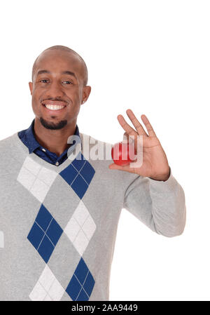 Ein afrikanischer amerikanischer Mann in einem Pullover, Lächeln hell und in seiner Hand einen roten Apfel, auf weißem Hintergrund Stockfoto