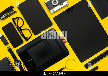 Schwarze Objekte aus dem Büro auf einem gelben Hintergrund. Arbeit und Kreativität. Social media Konzept hero Header Image. Ansicht von oben. Immer noch leben. Platz kopieren Stockfoto