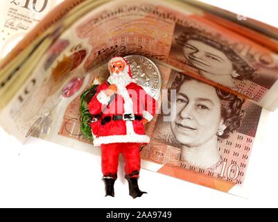 Ein Weihnachtsmann Figur stehend vor einige neue zehn Pfund Noten. England Großbritannien Stockfoto