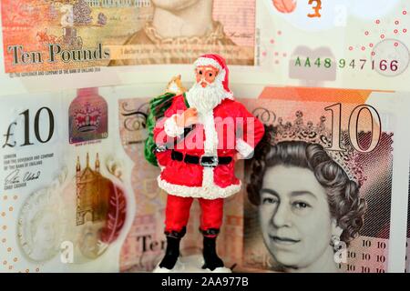 Ein Weihnachtsmann Figur stehend vor einige neue zehn Pfund Noten. England Großbritannien Stockfoto