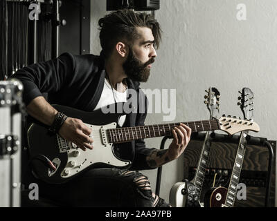 Foto eines Mannes mit Bart sitzt und seine elektrische Gitarre spielen in einem Tonstudio. Stockfoto