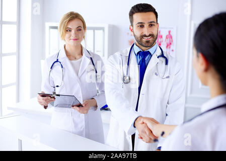 Junge arabische Arzt schüttelt Hände mit einer Krankenschwester in einem Krankenhaus. Vor dem Hintergrund des menschlichen Körpers Stockfoto