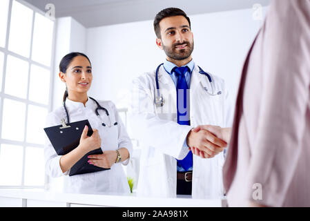 Junge arabische Arzt schüttelt Hände mit einem Patienten in einem Krankenhaus Stockfoto