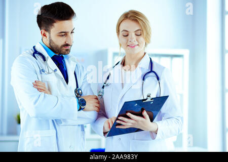 Zwei Ärzte halten einen Ordner und sprechen von Patienten Stockfoto